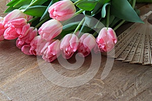 Pink tulips with fan on wooden board