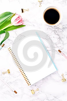 Pink tulips with festive stationary and coffee on white marble background. Online and remote work and learning, home