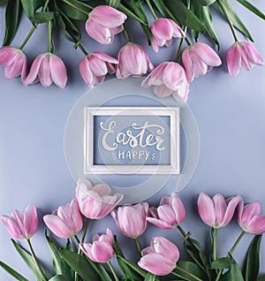 Pink tulips flowers on blue background with frame for text. Waiting for spring. Happy Easter card. Flat lay, top view