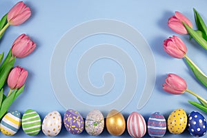 Pink tulips flowers and colourful eggs on pink background. Card for Happy Easter. Waiting for spring.