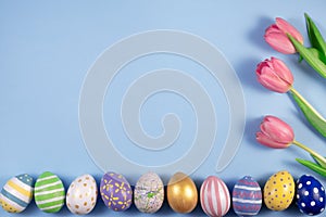 Pink tulips flowers and colourful eggs on pink background. Card for Happy Easter. Waiting for spring.