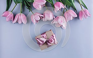 Pink tulips flowers and gift over light blue background. Greeting card or wedding invitation.