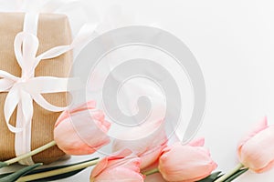 Pink tulips and gift box with ribbon on white background, flat lay. Stylish tender image. Happy womens day. Greeting card with