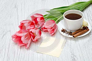 Pink tulips, mug of coffee and cinamon. Empty postcard. Llight w