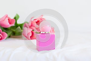 Pink tulips and perfume bottle on white background