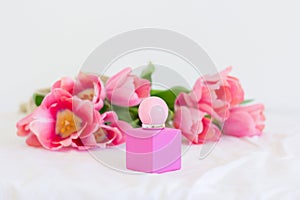 Pink tulips and perfume bottle on white background