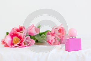 Pink tulips and perfume bottle on white background