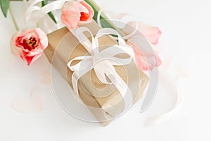 Pink tulips with ribbon and gift box on white background. Stylish soft image of spring flowers. Happy womens day. Greeting card