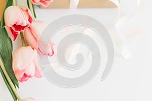 Pink tulips with ribbon on white background with gift box. Stylish tender image. Happy womens day. Greeting card with space for