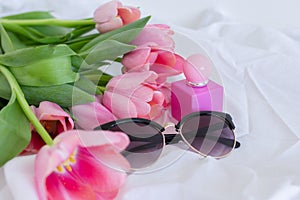 Pink tulips, sunglasses and perfume bottle on white background, women cosmetics set