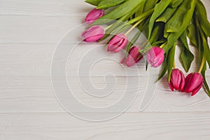 Pink tulips on a white wooden table.