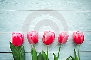 Pink tulips on wooden background. Flat lay, top view, copy space.