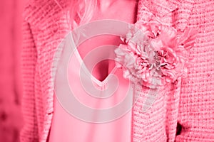 A pink tweed jacket with a brooch in the shape of a flower, toned in pink
