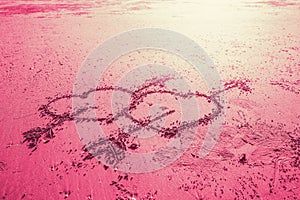 Pink two love heart sign with cupid arrow hand draw on the beach