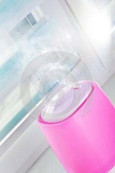 Pink ultrasonic humidifier on a window moistens dry air