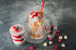 Pink unicorn milkshake with whipped cream and dessert, dripping sauce and candy