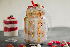 Pink unicorn milkshake with whipped cream and sweet dessert, dripping sauce and candy