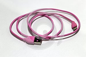 Pink used USB plug with cable on the white background.