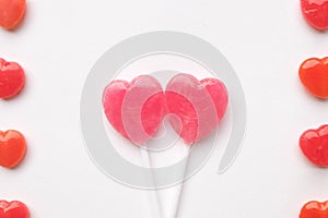 Pink Valentine`s day heart shape lollipop small red candy in cute pattern on empty white paper background. love concept. top view.