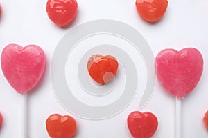 Pink Valentine`s day heart shape lollipop small red candy in cute pattern on empty white paper background. love concept. top view.