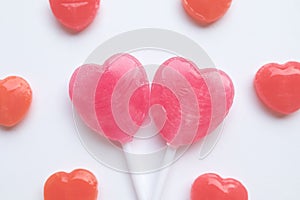 Pink Valentine`s day heart shape lollipop small red candy in cute pattern on empty white paper background. love concept. top view.