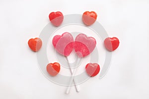 Pink Valentine`s day heart shape lollipop small red candy in cute pattern on empty white paper background. love concept. top view.