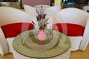 Pink vase with a summer bouquet of lavender flowers on a glass table with a transparent glass against the background of white red