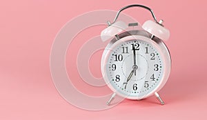 Pink vintage alarm clock 7 o`clock on pink background with copy space