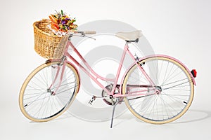 Pink vintage bicycle whith flower basket isolated on white backg photo