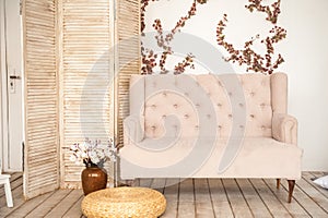 Pink vintage sofa and screen in rustic style. Interior of a bright Scandinavian living room with flowers on the wall