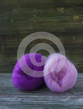 Pink and violet balls of mohair wool yarn for knitting, crochet on wooden rustic background