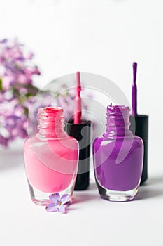 Pink and violet nail polish bottles on white background