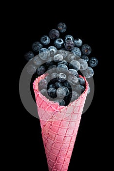 Pink wafer cone with frozen blueberry fruits. Ice cream