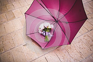 Pink wedding bouquet next to a red umbrella a rainy wedding day, nice melancholic photo