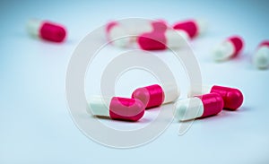 Pink-white capsule pill on blurred capsule background. Antibiotic drug resistance. Antimicrobial capsule pills. Pharmacy drugstore