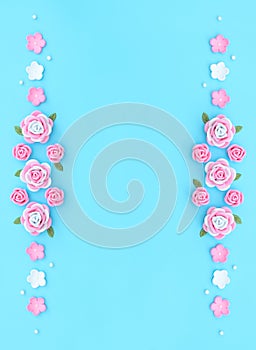 Pink and white flowers made of foamiran with green leaves and white beads on blue background. Mother day, Valentine day, Wedding,