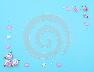 Pink and white flowers made of foamiran with green leaves and white beads on blue background. Mother day, Valentine day, Wedding,