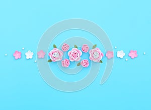 Pink and white flowers made of foamiran with green leaves and white beads on blue background. Mother day, Valentine day, Wedding,