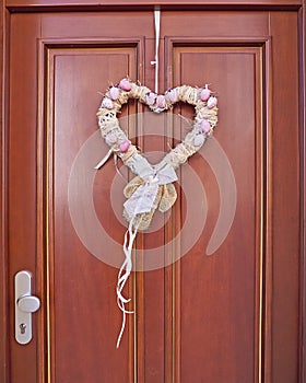 Pink white heart shaped wreath on solid wood house door