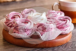 Pink and white marshmallows zephyr on a round wooden board wi