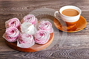 Pink and white marshmallows zephyr on a round wooden board wit