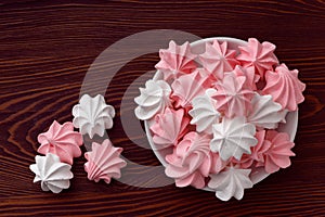 Pink and white meringues on a dark wooden table