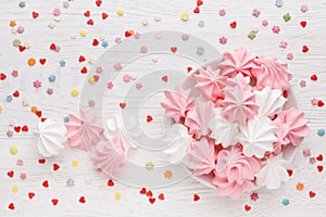 Pink and white meringues on a white wooden table