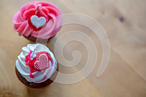 Pink and white muffins with heart on wooden ground in top view