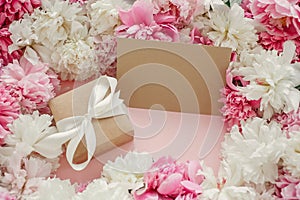 Pink and white peonies with empty card on pastel pink paper. Copy space. Happy mothers day, floral greeting card mockup.