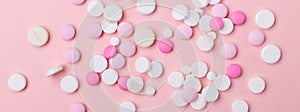 Pink and white pills on pink background. Heap of assorted various medicine tablets and pills. Horizontal banner