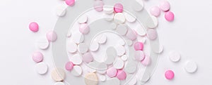 Pink and white pills on white background. Heap of assorted various medicine tablets and pills. Horizontal banner