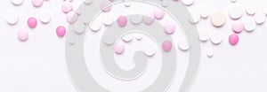 Pink and white pills on white background. Heap of assorted various medicine tablets and pills. Horizontal banner