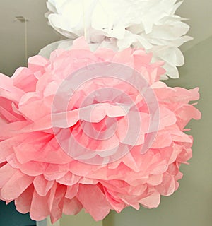 Pink and white pompoms hanging from a ceiling