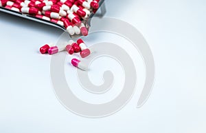 Pink-white and red-white capsule on white table and blurred stainless steel drug tray. Love pills for Valentine`s day concept.
